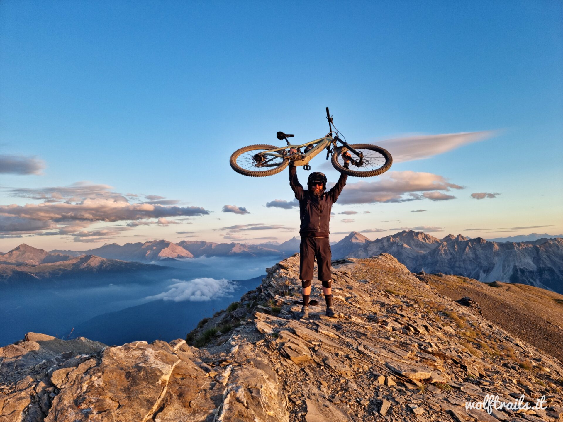 Mountain biker celebrating on a high-altitude ridge during an MTB tour in Bardonecchia Italian Alps