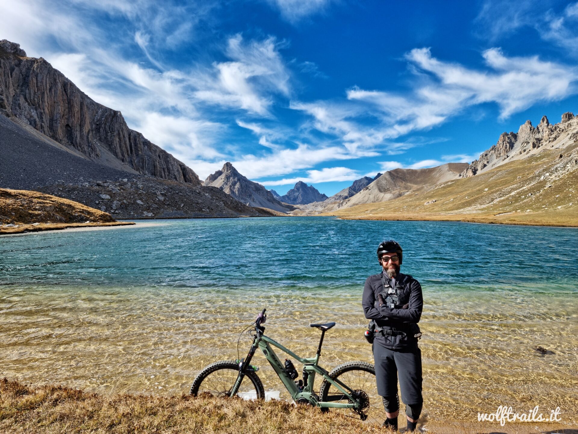 Mountain biker with e-MTB beside an alpine lake in Valle Stura, Western Alps