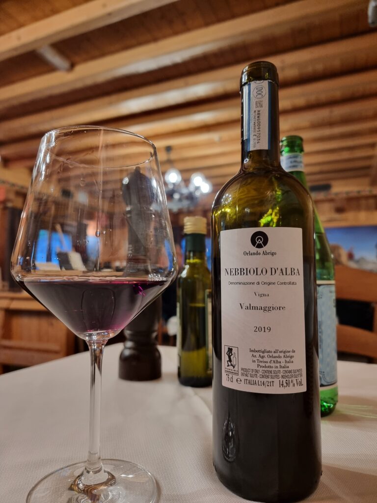 Bottle of Nebbiolo d’Alba and glass of red wine at a mountain restaurant during a WolfTrails MTB tour